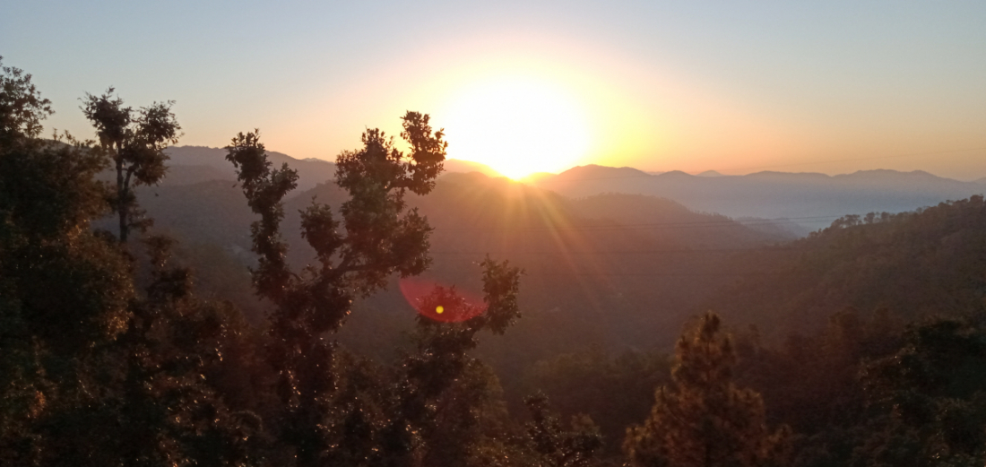 धनगढीः जंगलमा ढकमक्क लालीगुँरास। सबैतिर ठूला पहाड तथा उत्तरमा हिमालको दृश्य। पूर्वमा बिहानको उदाउँदो सूर्य।
